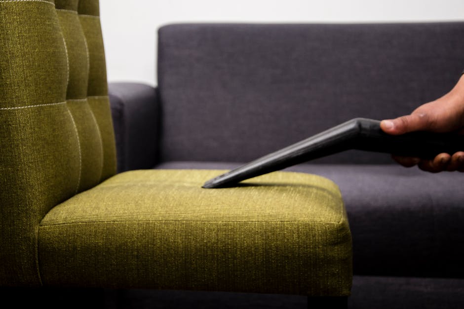 A clean, white upholstered sofa with button tufting on the backrest and rolled arms, situated against a white decorative wall panel in a well-lit room. The sofa’s fabric appears fresh and dust-free,